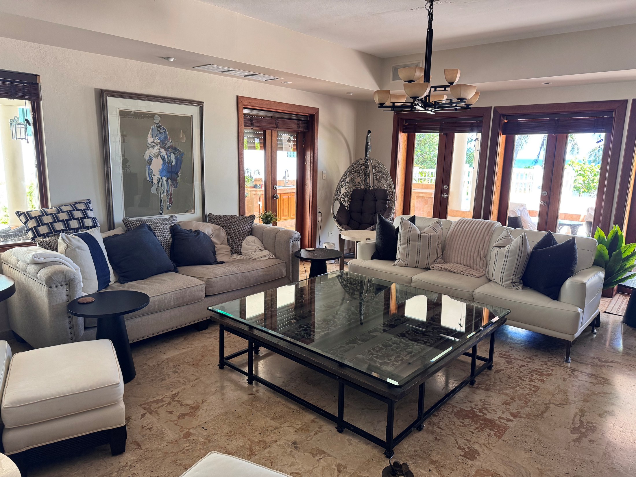 Living room with white and linen sofas opening through French doors to the ocean