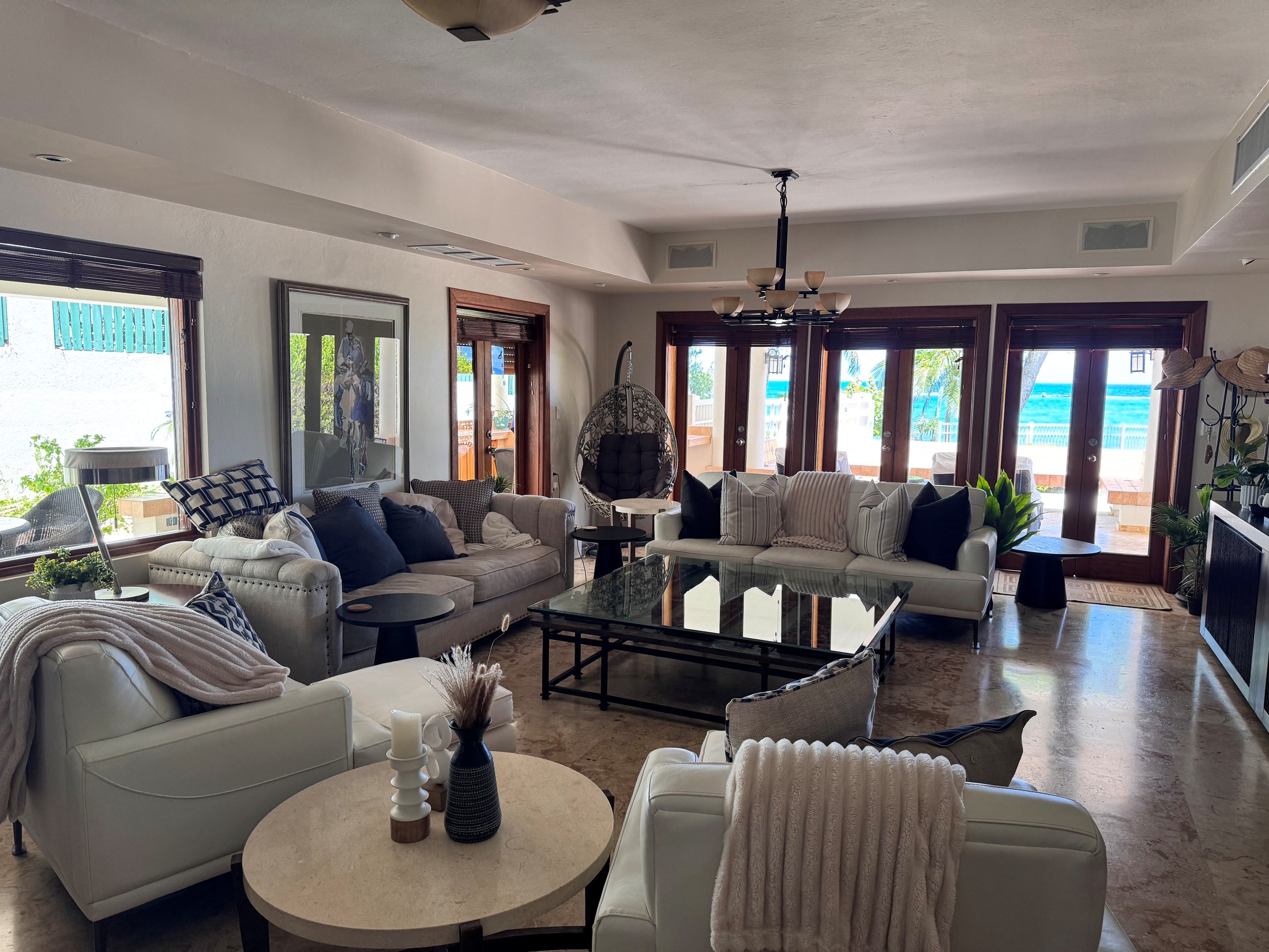 Living room seating around a glass coffee table with a hanging egg chair by the patio doors